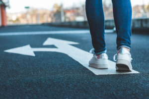 Woman walking on road with arrows pointing in different directions