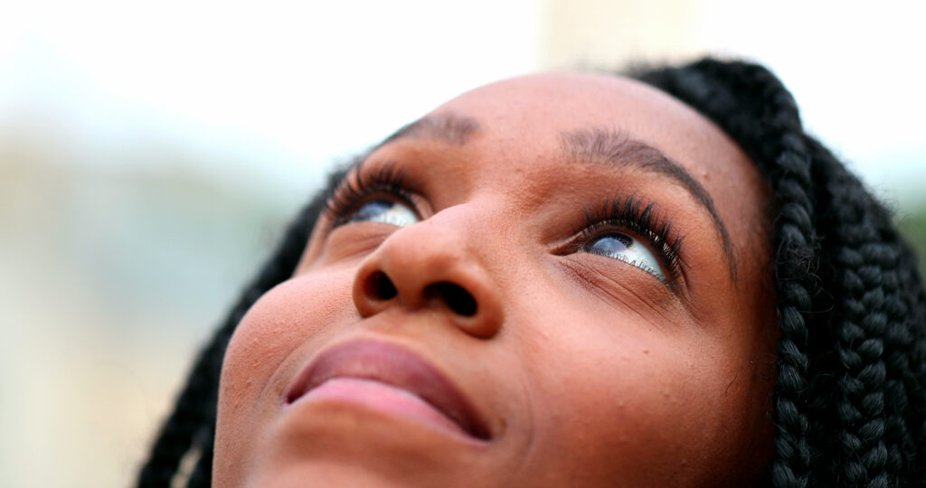 Young woman looking up to the sky faithfully