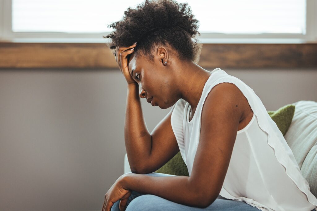 A woman with her hand on her forehead, looking tired and discouraged