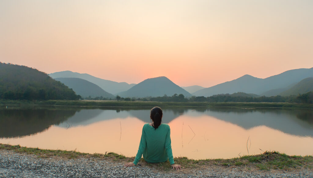 woman sitting quietly in front of a lake